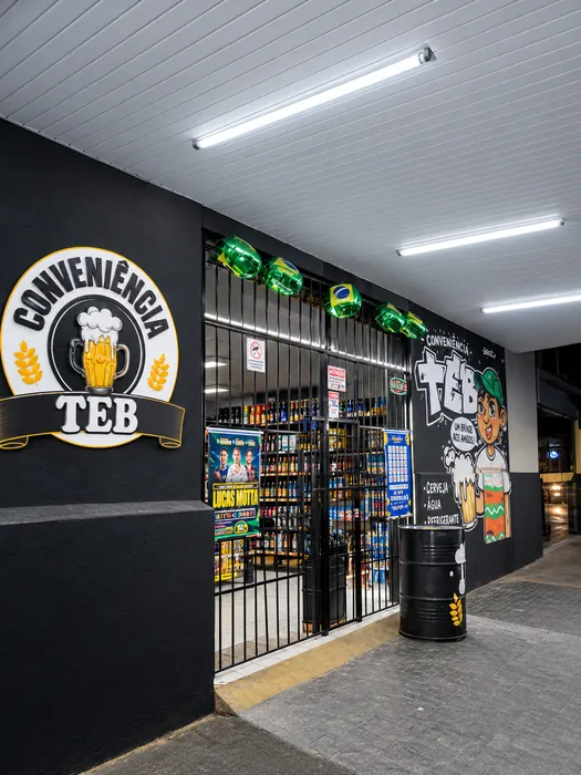Entrada da TEB Conveniência com logotipo na parede e prateleiras ao fundo